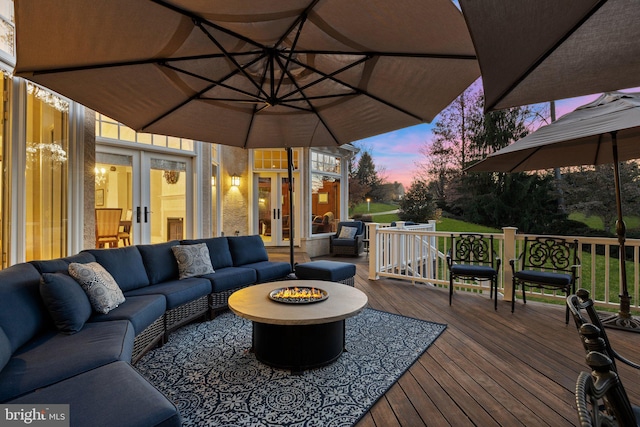 deck at dusk with an outdoor living space with a fire pit