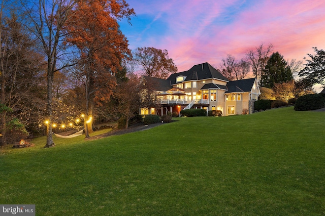 back house at dusk featuring a yard