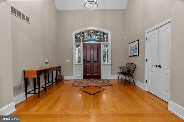 foyer featuring a high ceiling, wood-type flooring, and an inviting chandelier