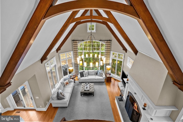 living room with vaulted ceiling with beams, light hardwood / wood-style floors, and a chandelier