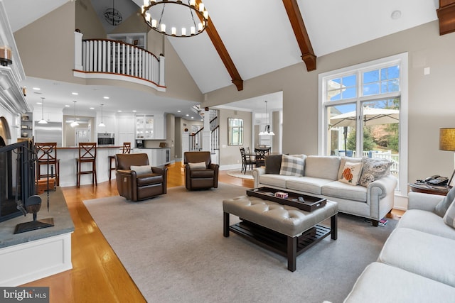 living room with beam ceiling, a wealth of natural light, light hardwood / wood-style floors, and a chandelier