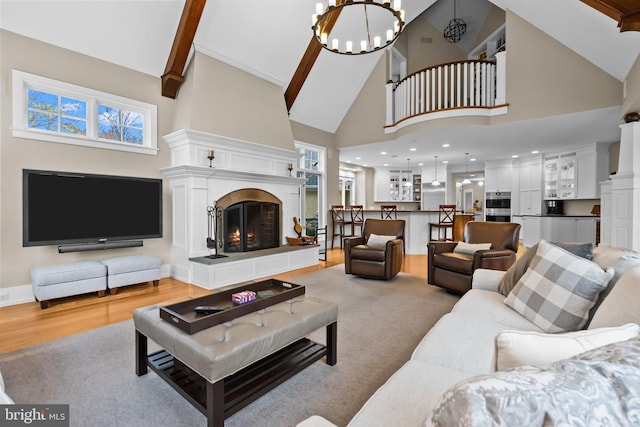 living room with an inviting chandelier, high vaulted ceiling, and light wood-type flooring