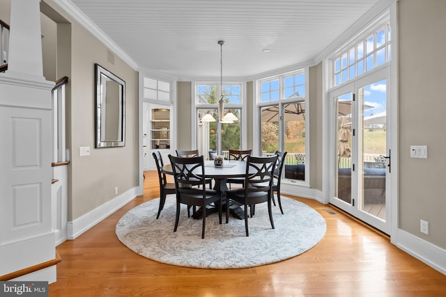 dining space featuring crown molding, a chandelier, and light wood-type flooring