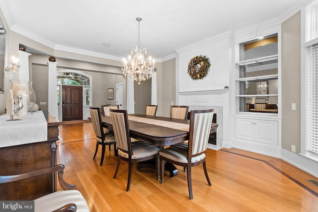 dining area with ornamental molding, built in features, a chandelier, and light hardwood / wood-style flooring