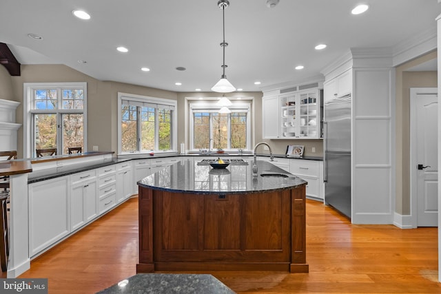 kitchen featuring decorative light fixtures, white cabinetry, sink, stainless steel built in fridge, and light hardwood / wood-style floors