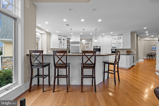 kitchen with white cabinetry, hanging light fixtures, a kitchen breakfast bar, and stainless steel appliances