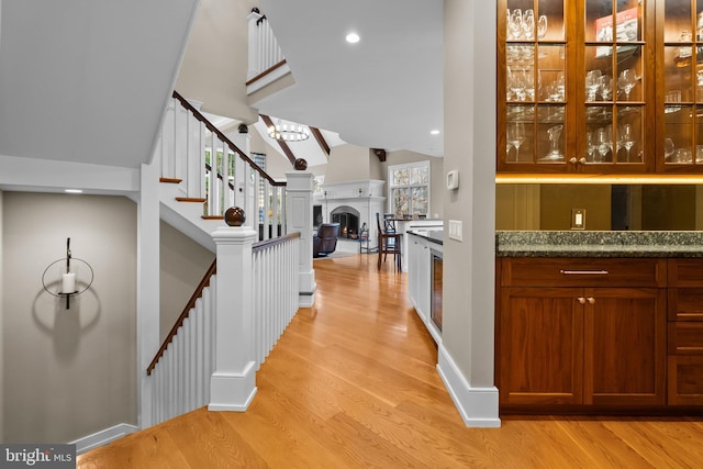 bar featuring lofted ceiling, stone counters, and light wood-type flooring