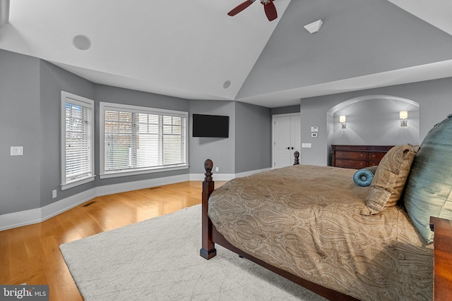 bedroom with hardwood / wood-style floors, high vaulted ceiling, and ceiling fan