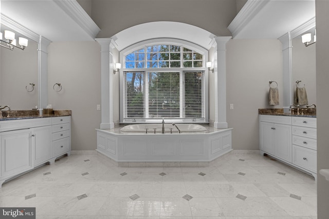 bathroom featuring ornate columns, vanity, vaulted ceiling, and a tub to relax in