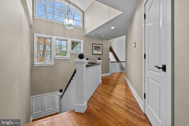 hall featuring a towering ceiling, a chandelier, and light hardwood / wood-style flooring