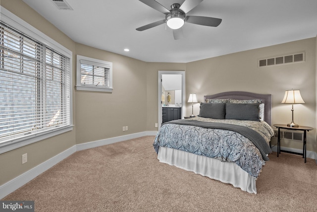 bedroom featuring light carpet, ceiling fan, and ensuite bathroom