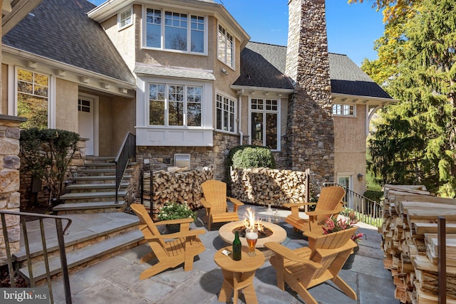 rear view of house featuring an outdoor fire pit and a patio