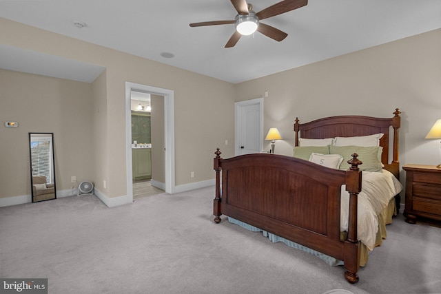 bedroom featuring ensuite bathroom, light colored carpet, and ceiling fan