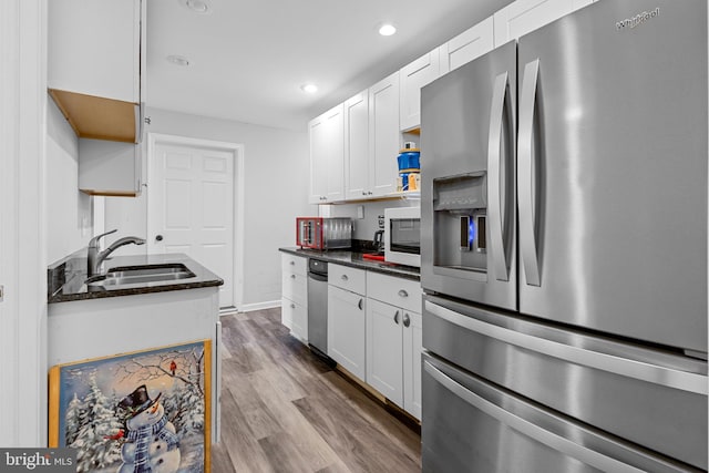 kitchen featuring hardwood / wood-style floors, dark stone counters, white cabinets, sink, and stainless steel fridge with ice dispenser