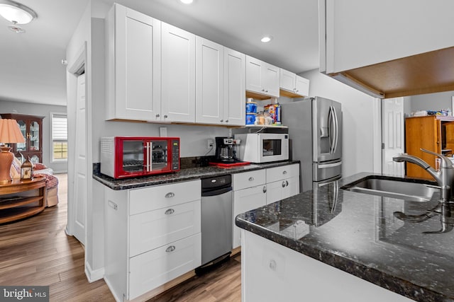 kitchen with white cabinetry, sink, stainless steel refrigerator with ice dispenser, dark stone counters, and light wood-type flooring