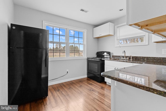 kitchen with black appliances, sink, dark stone countertops, light hardwood / wood-style floors, and white cabinetry