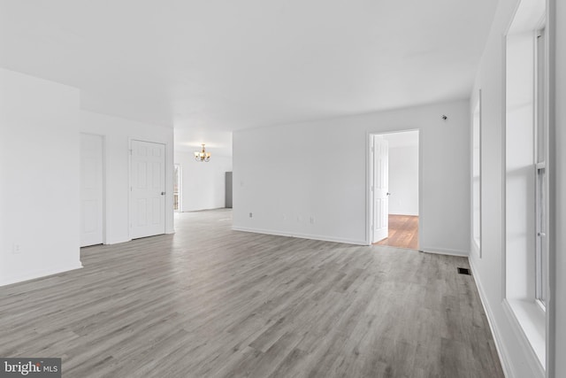 empty room featuring an inviting chandelier and light hardwood / wood-style flooring