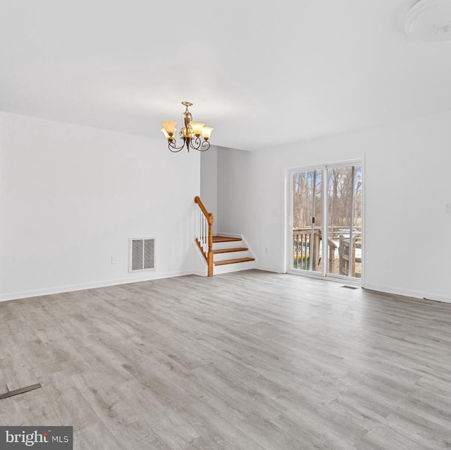 unfurnished living room featuring a chandelier and light hardwood / wood-style flooring