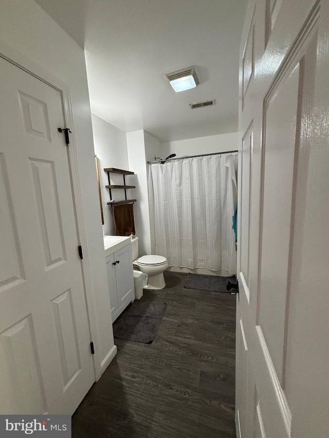 bathroom with wood-type flooring, vanity, toilet, and walk in shower