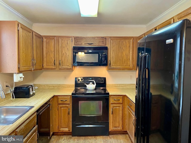 kitchen with sink, ornamental molding, and black appliances