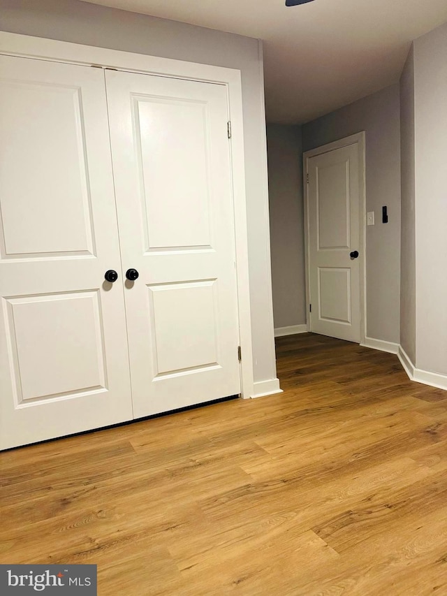 unfurnished bedroom with light wood-type flooring and a closet