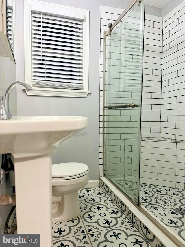 bathroom with tile patterned flooring, a shower with shower door, and toilet