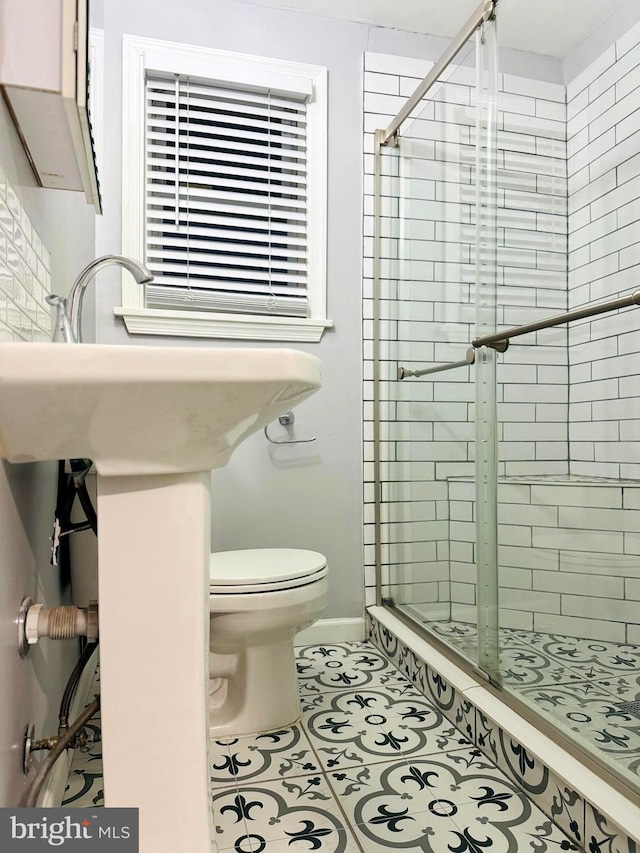 bathroom featuring tile patterned flooring, an enclosed shower, and toilet