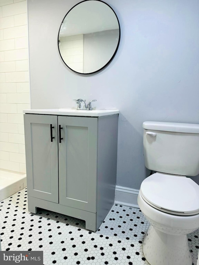 bathroom with a shower, tile patterned floors, vanity, and toilet