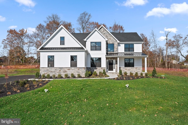 modern farmhouse style home featuring stone siding, a front lawn, and a standing seam roof