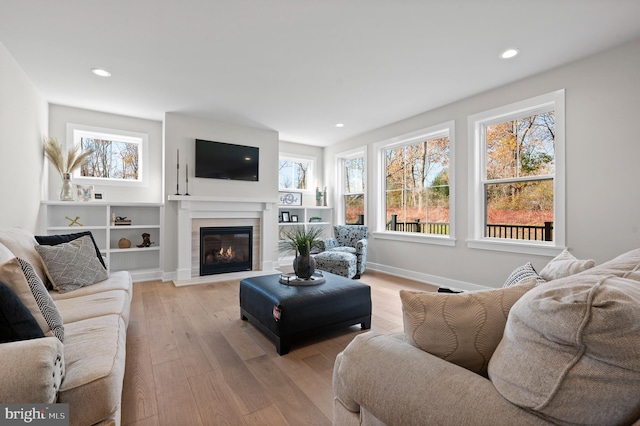 living room with plenty of natural light, a fireplace with flush hearth, light wood-style flooring, and baseboards