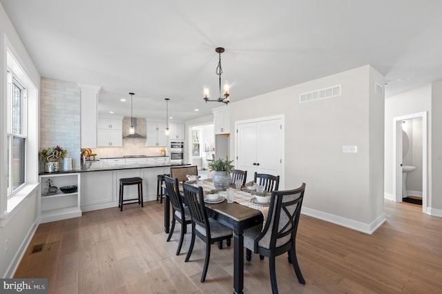 dining area with a chandelier, light wood-style flooring, recessed lighting, visible vents, and baseboards