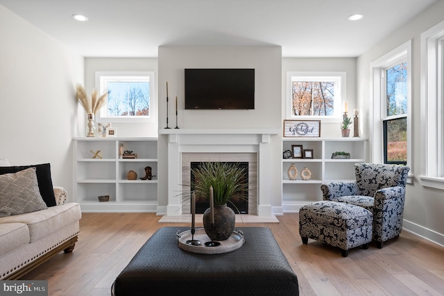 living area with a fireplace with flush hearth, light wood-type flooring, and recessed lighting