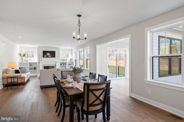 dining space featuring a healthy amount of sunlight, a fireplace, visible vents, and dark wood-style flooring