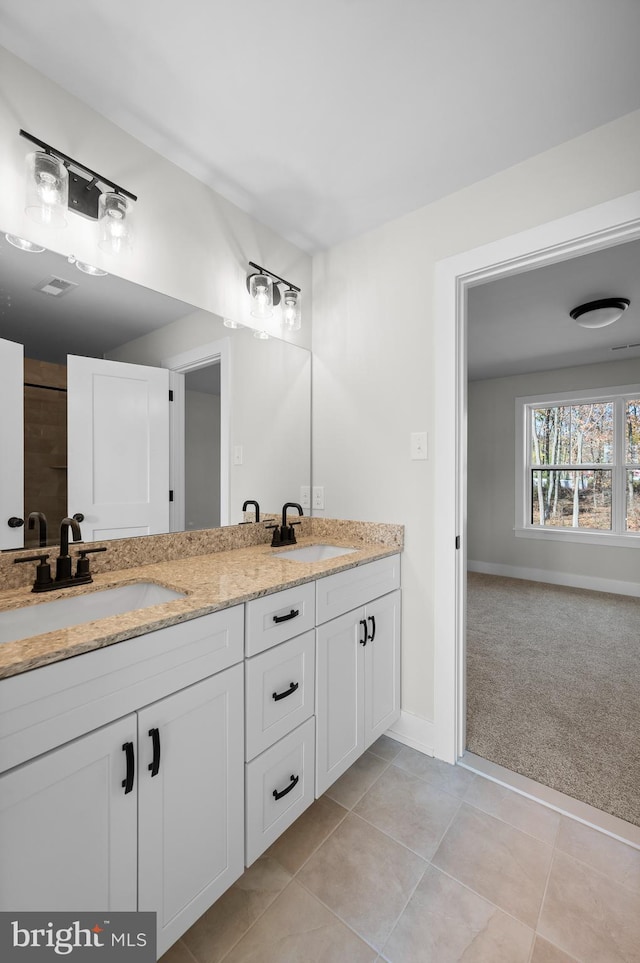 bathroom featuring double vanity, tile patterned flooring, a sink, and baseboards