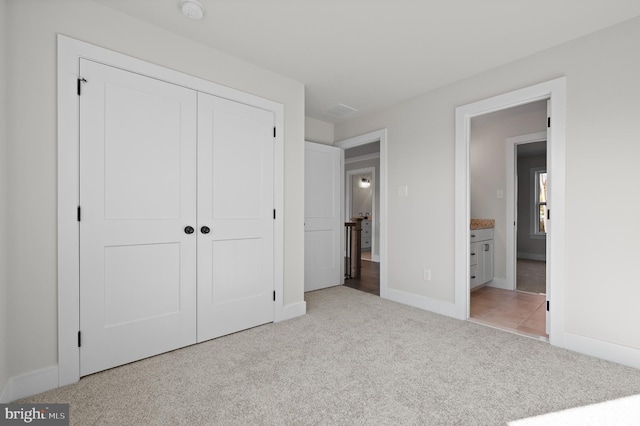 unfurnished bedroom featuring a closet, light colored carpet, and baseboards