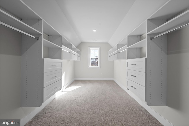 spacious closet with light carpet and vaulted ceiling