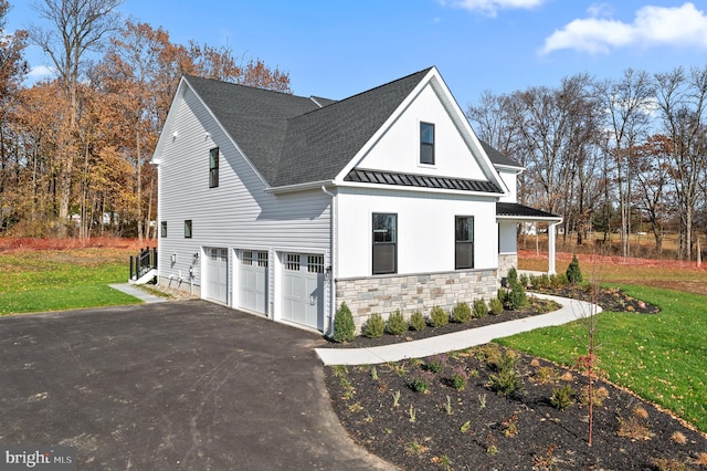 modern inspired farmhouse featuring aphalt driveway, a standing seam roof, metal roof, and a front lawn