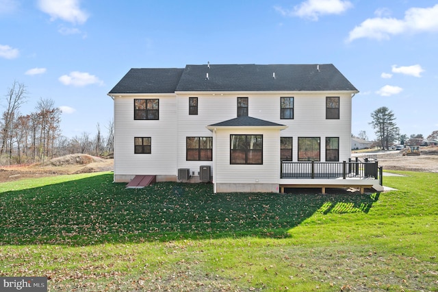 rear view of house with central AC unit, a deck, and a yard