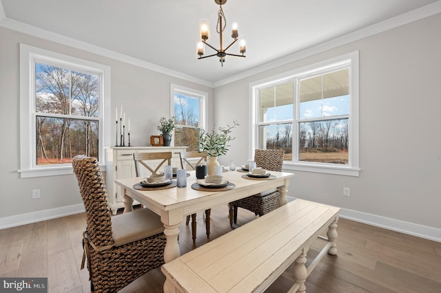 dining area with a chandelier, crown molding, baseboards, and hardwood / wood-style flooring