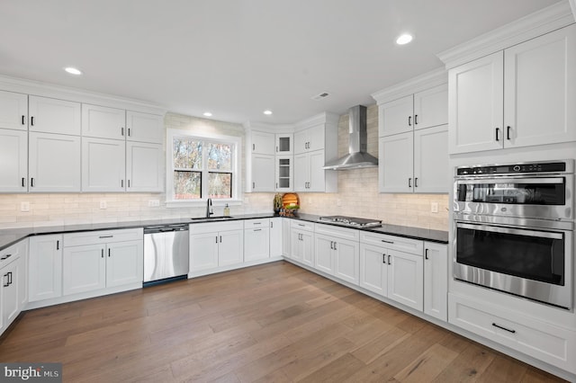 kitchen featuring dark countertops, wall chimney exhaust hood, glass insert cabinets, and stainless steel appliances