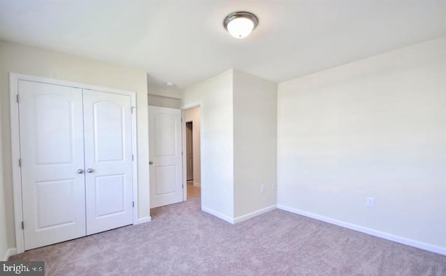 unfurnished bedroom featuring light carpet and a closet