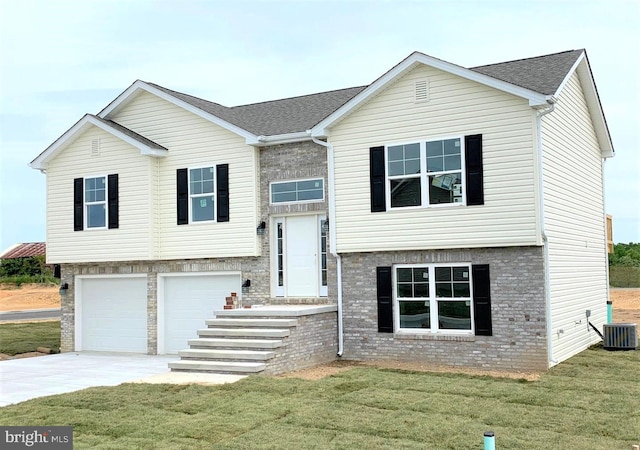 raised ranch featuring central AC unit, a garage, and a front lawn