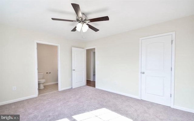 unfurnished bedroom with ceiling fan, light carpet, and ensuite bath