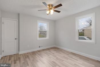 empty room with ceiling fan and light hardwood / wood-style flooring