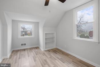 additional living space with ceiling fan, plenty of natural light, light hardwood / wood-style floors, and vaulted ceiling