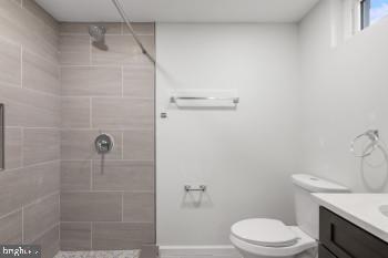 bathroom with toilet, vanity, and tiled shower