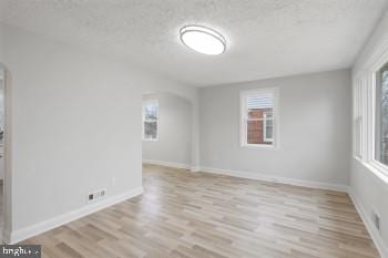 spare room with light hardwood / wood-style floors and a textured ceiling