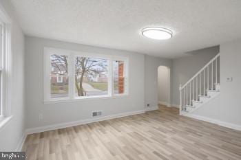 unfurnished room with a textured ceiling and light hardwood / wood-style flooring