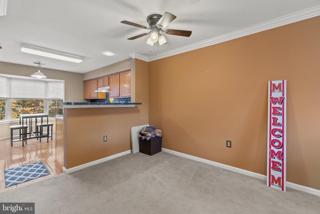 kitchen featuring ceiling fan, ornamental molding, light carpet, and hanging light fixtures