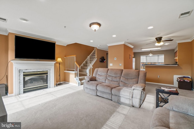 carpeted living room featuring a high end fireplace, ceiling fan, and crown molding